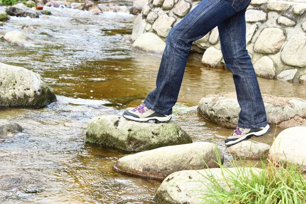 Botas de senderismo y piernas de una mujer sobre un arroyo de montaña —  Fotos de Stock