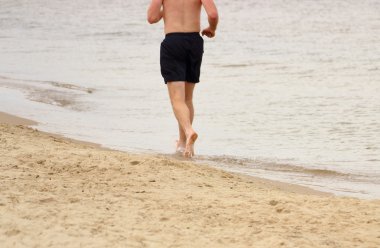 Yaz aylarında kumsalda koşan adam