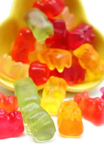 Colorful haribo bear candies pouring out of yellow bowl — Stock Photo, Image