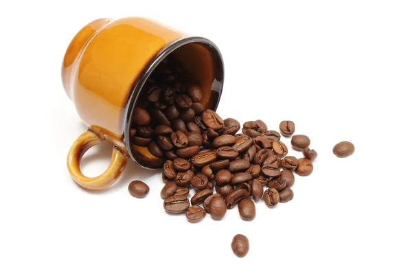 Copo virado e montão de grãos de café no fundo branco — Fotografia de Stock