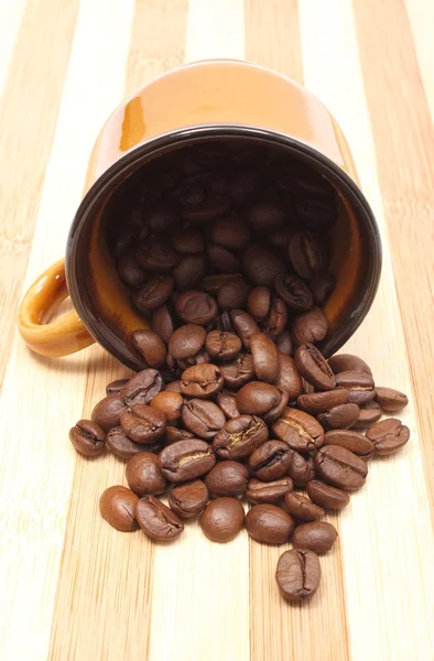 Перевернутая чашка и куча зерна кофе — стоковое фото