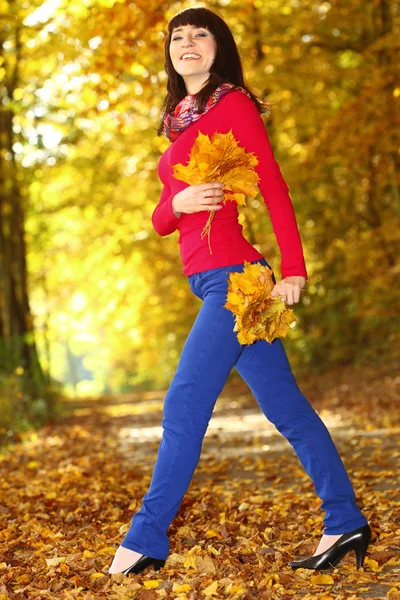 Donna in parco con foglie autunnali in mano — Foto Stock