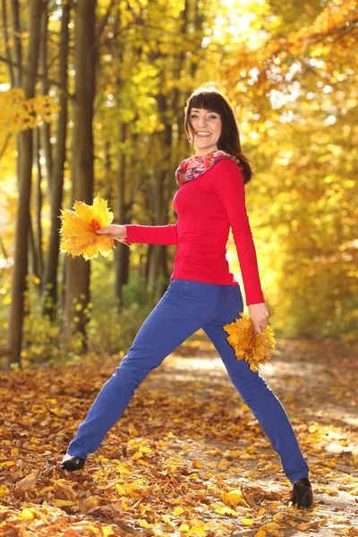Donna in piedi con foglie nel parco autunnale — Foto Stock