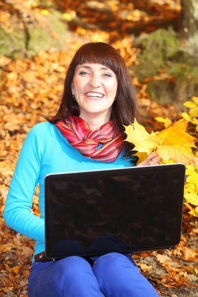 Mujer sonriente con portátil en el parque de otoño — Foto de Stock