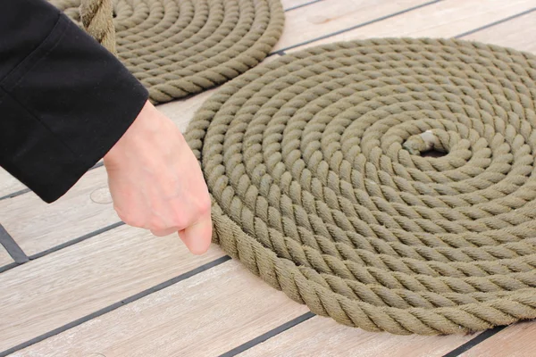 Frauenhand und dickes, spiralförmig umwickeltes Seil liegen an Deck des Schiffes — Stockfoto