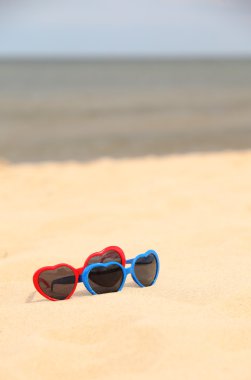 kum üzerinde kalp şeklinde renkli Güneş gözlükleri