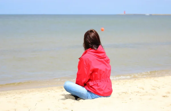 Woman sitting on the beach and looks at sea, summer time — Stock Photo, Image