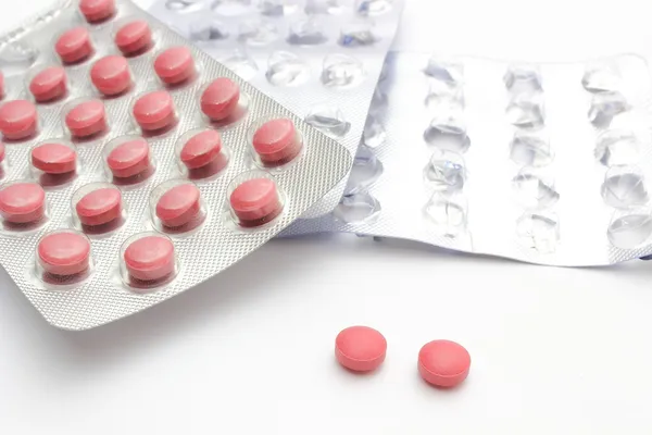 Dvě tablety s plné a prázdné pilulku puchýř. bílé pozadí — Stock fotografie