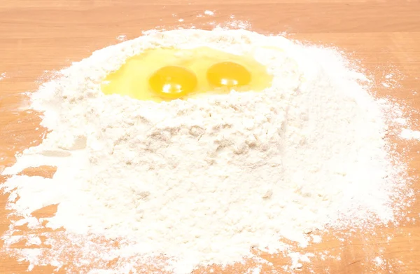 テーブルの上に横たわる小麦粉のヒープ内で壊れた卵 — ストック写真