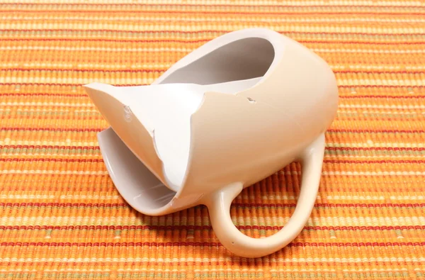 Broken mug, shattered cup on orange cloth — Stock Photo, Image