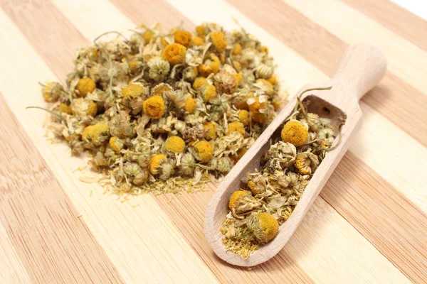 Heap of dried chamomile on wooden spoon — Stock Photo, Image