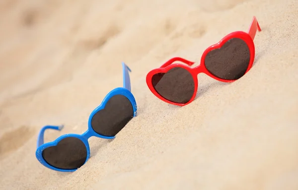 Colorati occhiali da sole a forma di cuore sulla sabbia — Foto Stock