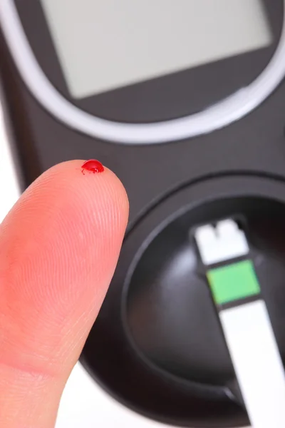 血およびブドウ糖メーターで指のクローズ アップ — ストック写真