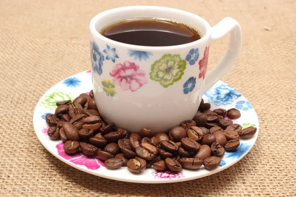 Hoop koffie korrels en kopje drank — Stockfoto