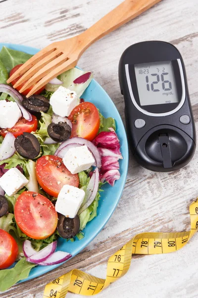 Glucometer with result of sugar level, cintimeter and fresh greek salad with feta cheese and vegetables. Best healthy food for diabetics, dieting and slimming