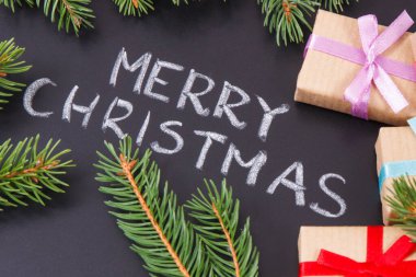 Yazı, Mutlu Noeller, kurdele ve yeşil ladin dallarıyla paketlenmiş hediyeler. Noel zamanı için dekorasyon