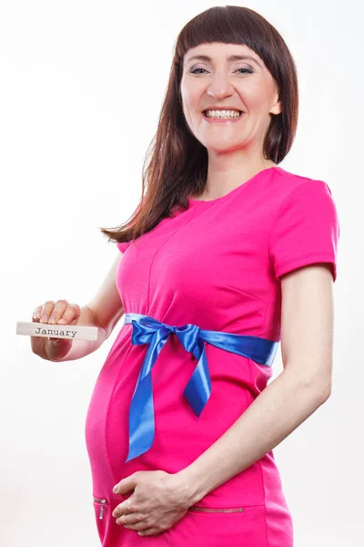 青いリボンとピンクのドレスを着て妊娠中の幸せな笑顔の女性と木製のキューブに書かれた単語1月を示しています 新生児や家族の拡大への期待 — ストック写真