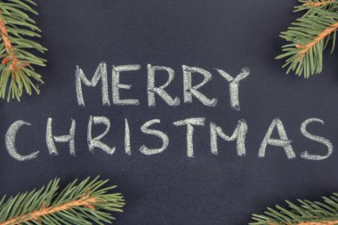 Yazılı Mutlu Noeller ve siyah arka planda yeşil ladin dalları. Noel zamanı için dekorasyon