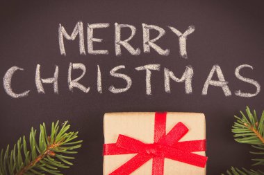 Yazılı Mutlu Noeller, siyah arka planda yeşil ladin dalları ve kurdele ile paketlenmiş hediye. Noel zamanı için dekorasyon