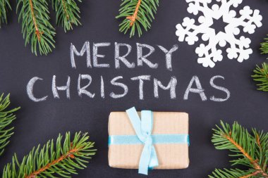 Yazılı Mutlu Noeller, siyah arka planda yeşil ladin dalları ve kurdele ile paketlenmiş hediye. Noel zamanı için dekorasyon