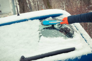Araba ve ön camlardan kar temizleyen bir kadın eli. Ulaşım sırasında kış sorunları