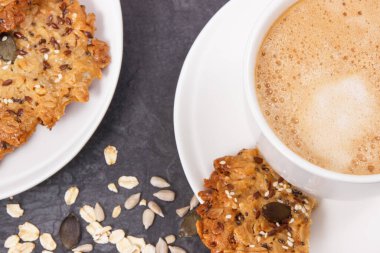 Sütlü kahve ve beyaz tabakta taze ev yapımı yulaf ezmeli kurabiye. Lezzetli çıtır tatlı.