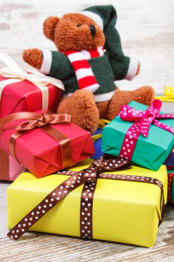 Kabarık oyuncak ayı ve Noel, doğum günü, Sevgililer veya diğer kutlama eski ahşap beyaz masa üzerinde kaydırılan renkli hediyeler yığını