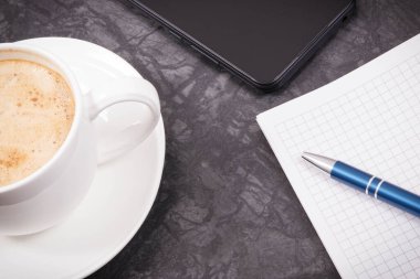Cep telefonu, not almak için sütlü kahve ve not defteri. Çalışma ya da dinlenme zamanı
