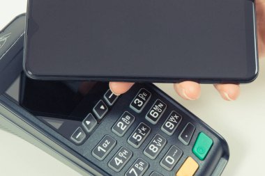 Kredi kartı okuyucu ve cep telefonunu nakit ödemelerde kullanıyor. Ödeme terminali. Finans ve bankacılık kavramı