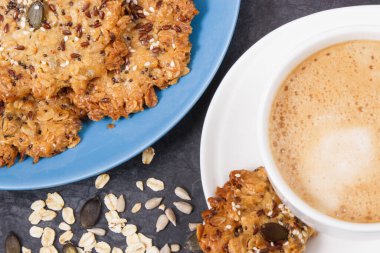 Sütlü kahve ve mavi tabakta taze ev yapımı yulaf ezmeli kurabiye. Lezzetli çıtır tatlı.