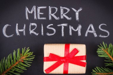 Yazı, Mutlu Noeller, kurdele ve yeşil ladin dallarıyla paketlenmiş hediye. Noel zamanı için dekorasyon