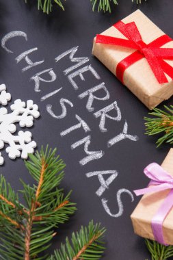 Yazı, Mutlu Noeller, kurdele ve yeşil ladin dallarıyla paketlenmiş hediyeler. Noel zamanı için dekorasyon