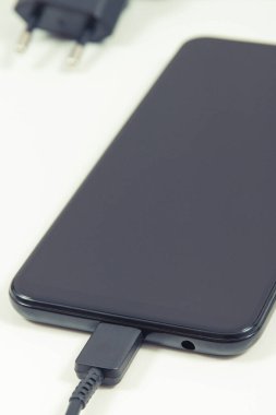 Şarj aletine bağlı akıllı telefon. Telefon şarj oluyor. Beyaz arkaplan