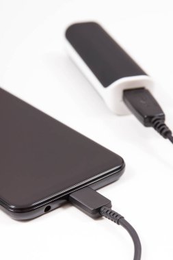 Dış siyah enerji bankası akıllı telefon veya cep telefonunu şarj ediyor. Beyaz arkaplan