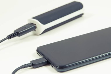 Elektrik prizi bağlı akıllı bir telefon. Telefon şarj oluyor. Beyaz arkaplan