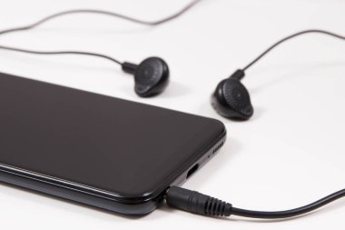 Cep telefonu, kulaklıklı akıllı telefon. Elektronik ekipman kullanarak. Beyaz arkaplan