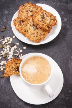 Sütlü kahve ve beyaz tabakta taze yulaf ezmeli kurabiye. Lezzetli çıtır tatlı.