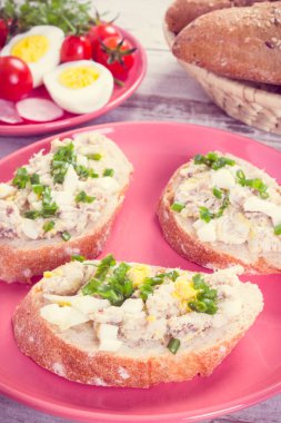 Klasik fotoğraf, ev yapımı uskumru ya da ton balığı ezmesi, yumurta, domates, turp ve sepette taze ekmek.