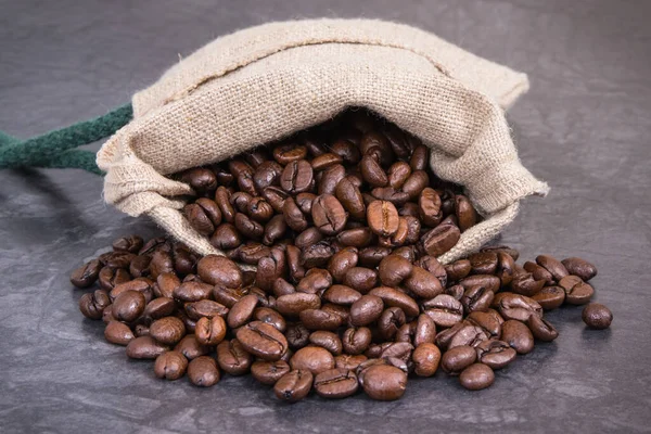 Haufen Dunkel Gerösteter Kaffeekörner Jutebeutel Auf Betonkonstruktion — Stockfoto