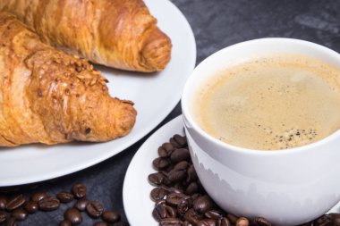 Kahvaltı için beyaz cam kahve ve taze pişmiş kruvasan.