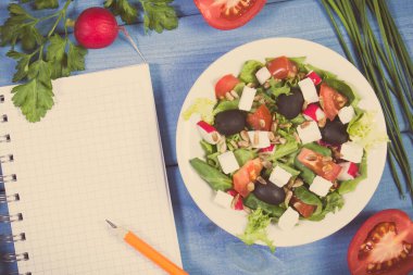Not defteri ve peyniriyle birlikte notlar için taze Yunan salatası. Sağlıklı beslenme
