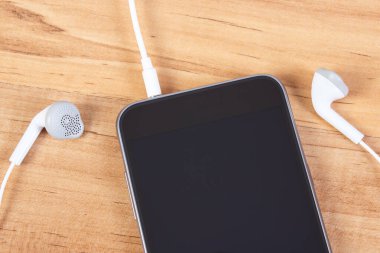 Cep telefonu, ahşap masaya bağlı kulaklıklı akıllı telefon.