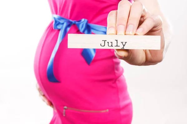 Kobieta Ciąży Ubrana Różową Sukienkę Niebieską Wstążką Napisem July Drewnianej — Zdjęcie stockowe
