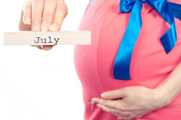 Kobieta Ciąży Różowej Sukience Niebieską Wstążką Napisem July Drewnianej Kostce — Zdjęcie stockowe