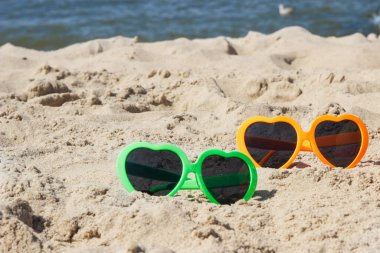 Kumsalda kumsalda renkli güneş gözlükleri. Güneş banyosu sırasında güneş koruması. Seyahat ve tatil zamanı kavramı