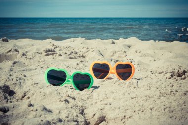 Kumsalda kumsalda güneşten korunmak için güneş gözlüğü. Seyahat ve tatil zamanı kavramı