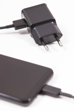 Şarj cihazına bağlı cep telefonu. Akıllı telefon şarj oluyor. Beyaz arkaplan