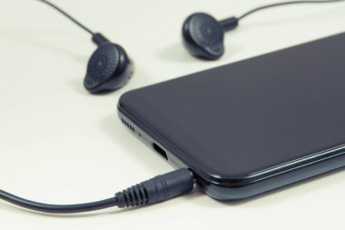 Cep telefonu, kulaklıklı akıllı telefon. Müzikle rahatlama zamanı. Elektronik ekipman kullanarak. Beyaz arkaplan