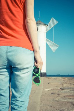 Swinoujscie 'nin batı dalgasında kalp şeklinde güneş gözlüklü bir kadın. Arka planda Windmill Stawa Mlyny karakteristik yön bulma işareti var. Yaz ve tatil zamanı