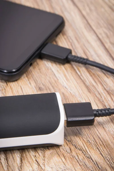 External powerbank using to charge empty battery of black smartphone or mobile phone